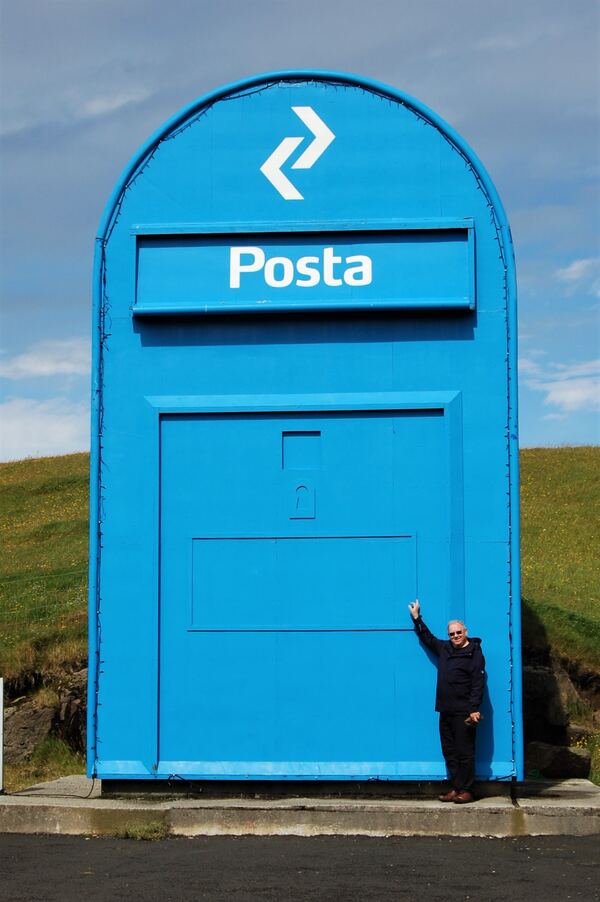 A giant blue Posta postbox, several times the height of the man standing beside it